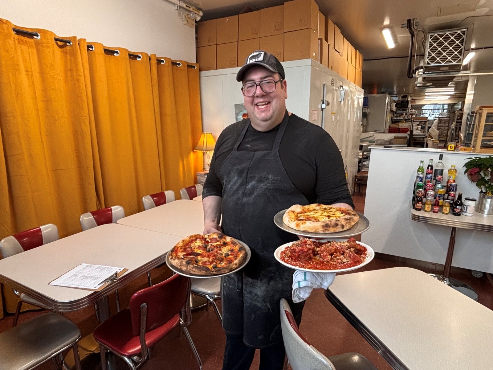 G Pizzas owner Giuseppe Sacchetti holding pizzas and meatballs in Montreal