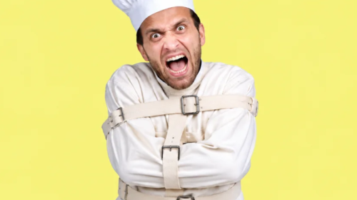 A man wearing a white chef's hat and a white straitjacket screams with wide eyes and an open mouth, looking directly at the viewer. His face is contorted in an expression of extreme frustration or madness, and his arms are bound across his chest by the straitjacket's straps. The background is a solid bright yellow.